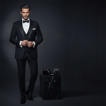 Load image into Gallery viewer, Man in a black tuxedo with accessories on a dark background, promoting 'The Everest Package' which includes 2 piece tuxedo set with vest or cummerbund, french cuff or convertible cuff white tuxedo shirt, Bow tie or Tie, Studs and cufflink set and black patent shoes. 
