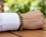 Load image into Gallery viewer, Close up of man wearing an African Turquoise and Jasper Bracelet accented by 18k gold-plated stainless steel  Exotic Elegance. Natural Detail. 

