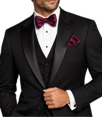 Load image into Gallery viewer, A man wearing a black tuxedo with satin lapels, a matching black vest, a white dress shirt, Sangria  bow tie, and matching pocket square, photographed against a plain white background.
