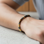 Load image into Gallery viewer, Close up of a man wearing Our genuine Pyrite and Tiger Eye bracelet with fluted 18k gold-plated spacers crafted from stainless steel, ensuring they won’t tarnish or lose their luster, even with daily wear.  .2 inches wide, it sits comfortably under a dress shirt or alongside a luxury watch. 
